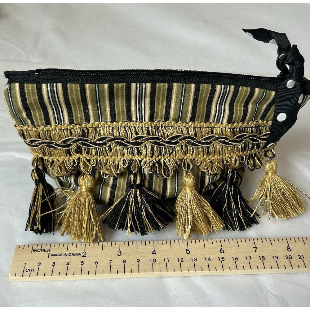 cosmetic bag featuring a striped fabric with gold tassel fringe and trim.